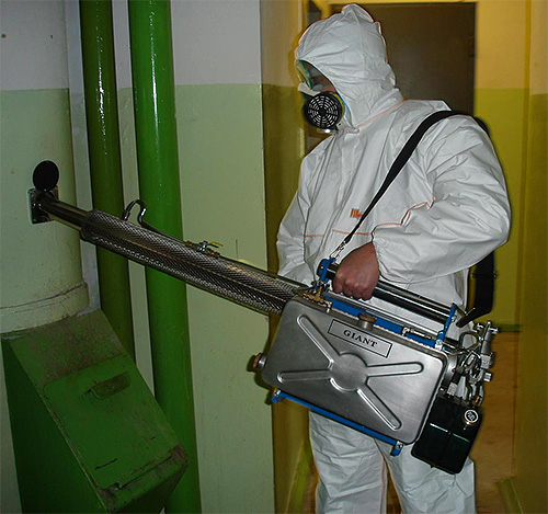 Fotografija prikazuje radnika za suzbijanje štetočina s generatorom vruće magle.